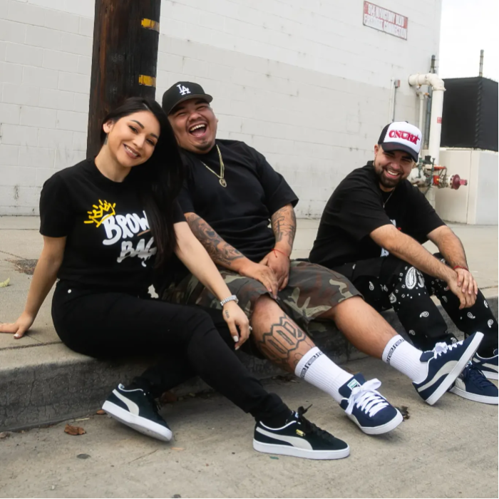 three people sitting on curb wearing puma suede shoes