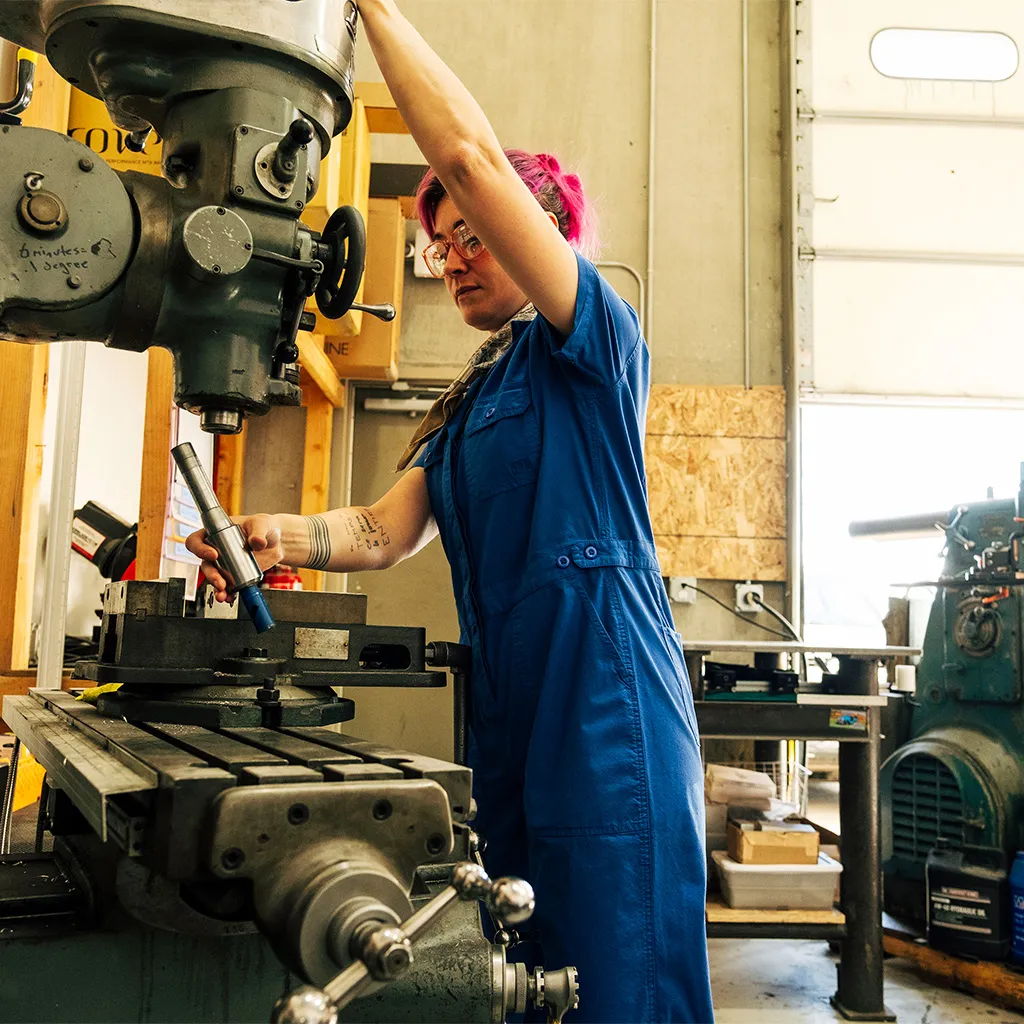 Person operating a milling machine in a workshop setting.