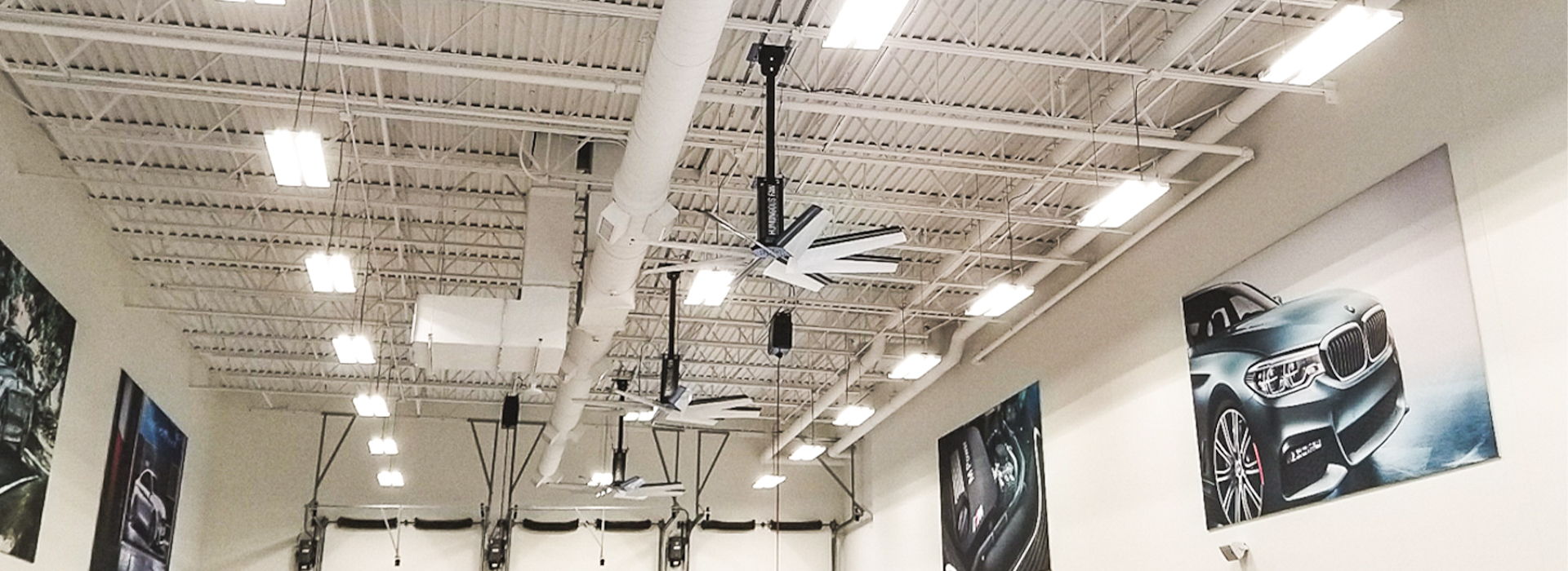 Interior of a large room with ceiling fans and automotive wall art.