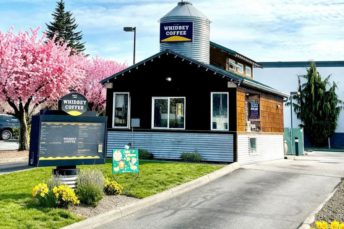Whidbey Coffee building with cherry blossoms and a silo in Burlington, Washington.