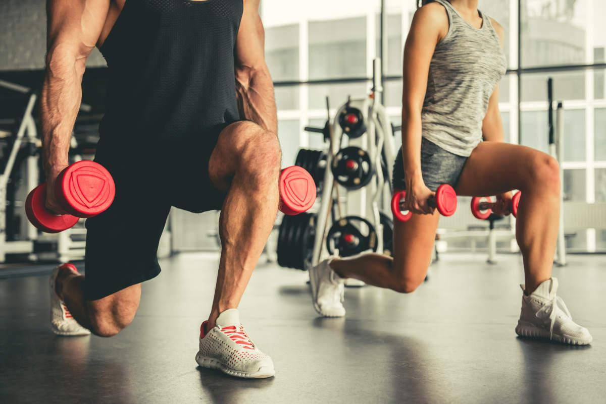 Attractive sports people are working out with dumbbells in gym  | Best Superset Hamstring Exercises You Need To Try