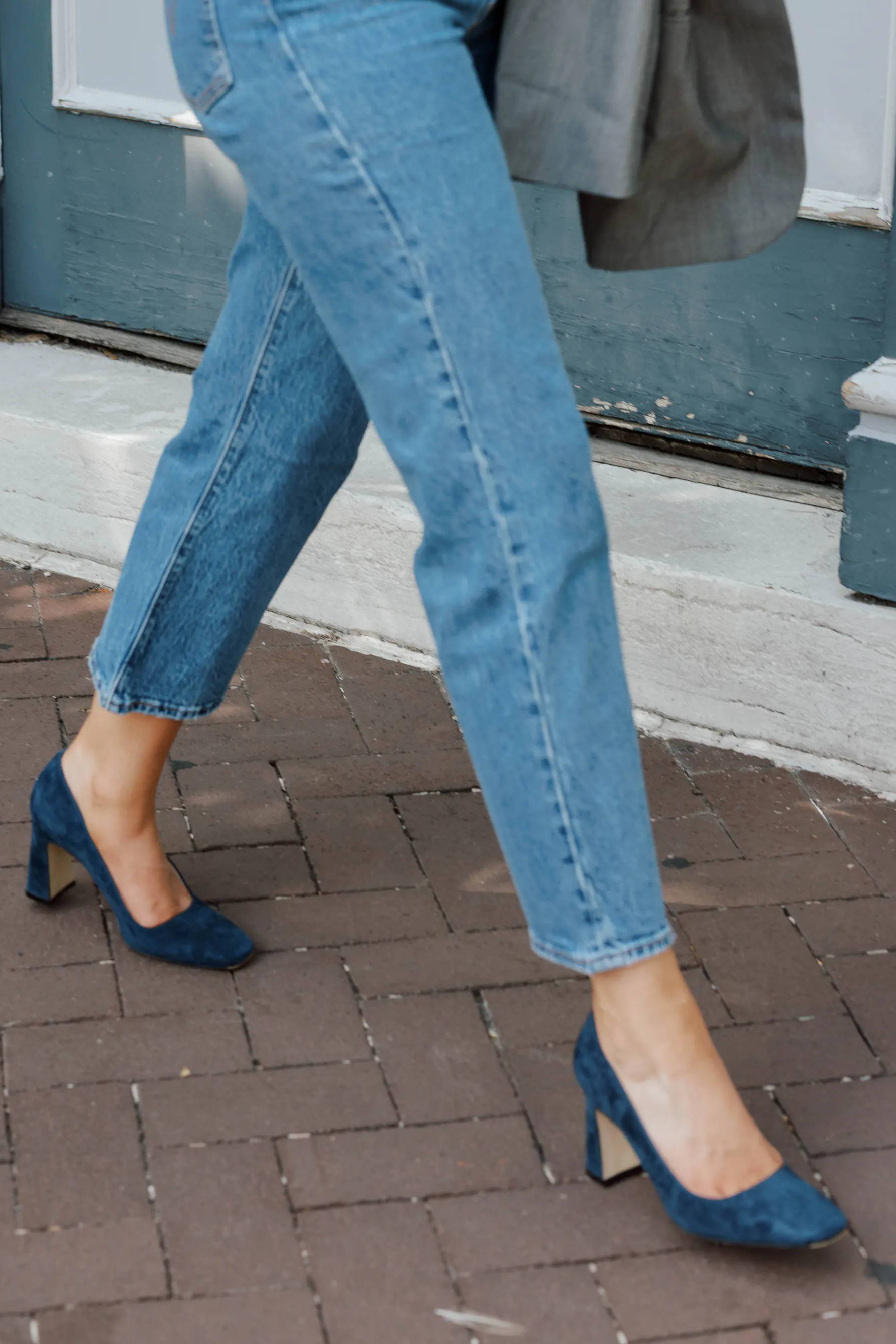 Person walking in stylish outfit with denim jeans and heels.