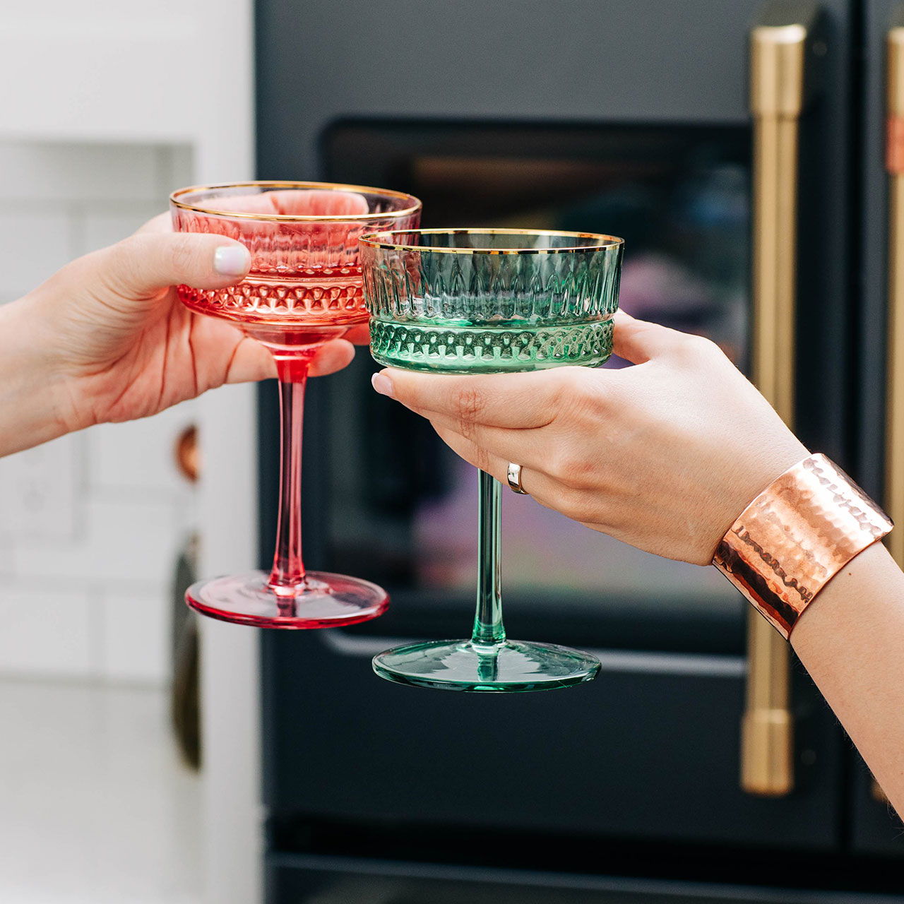 Two hands clinking colorful glasses in celebration.