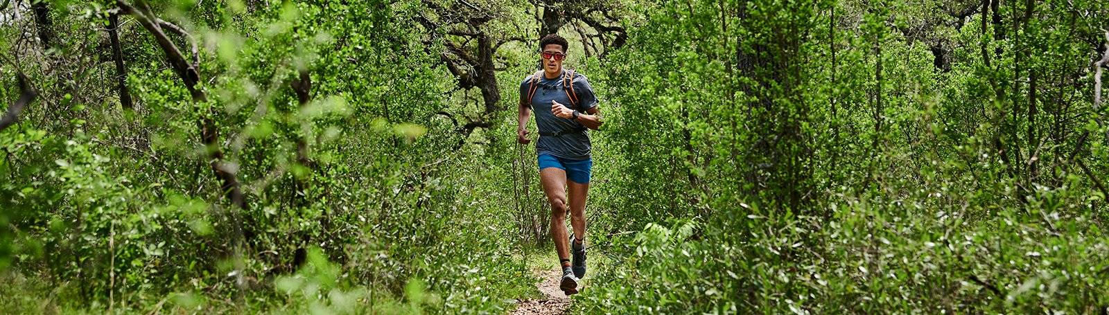 A runner on a wooded trail wearing a Garmin fenix 7 GPS outdoor watch