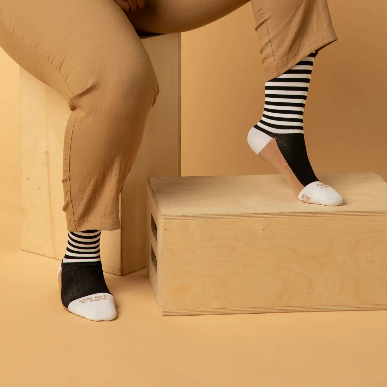 Ease by Therafirm Patterned Compression Socks; woman sitting on wood blocks in stylish socks