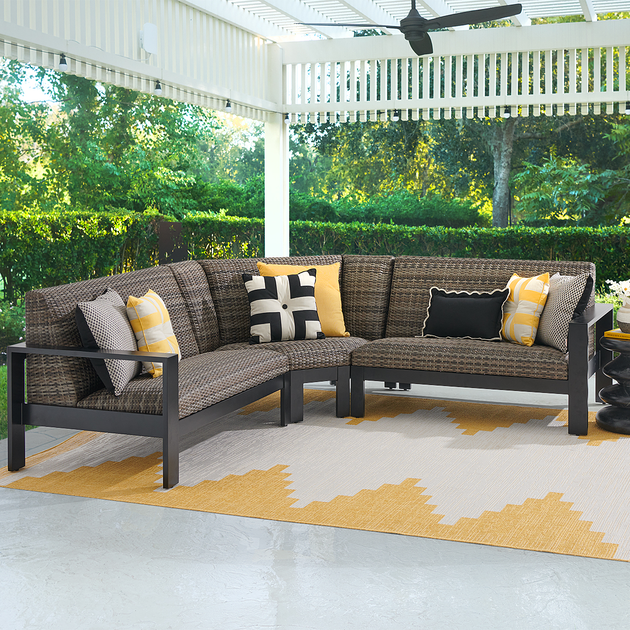 Outdoor sectional sofa with cushions on a patio under a covered area.