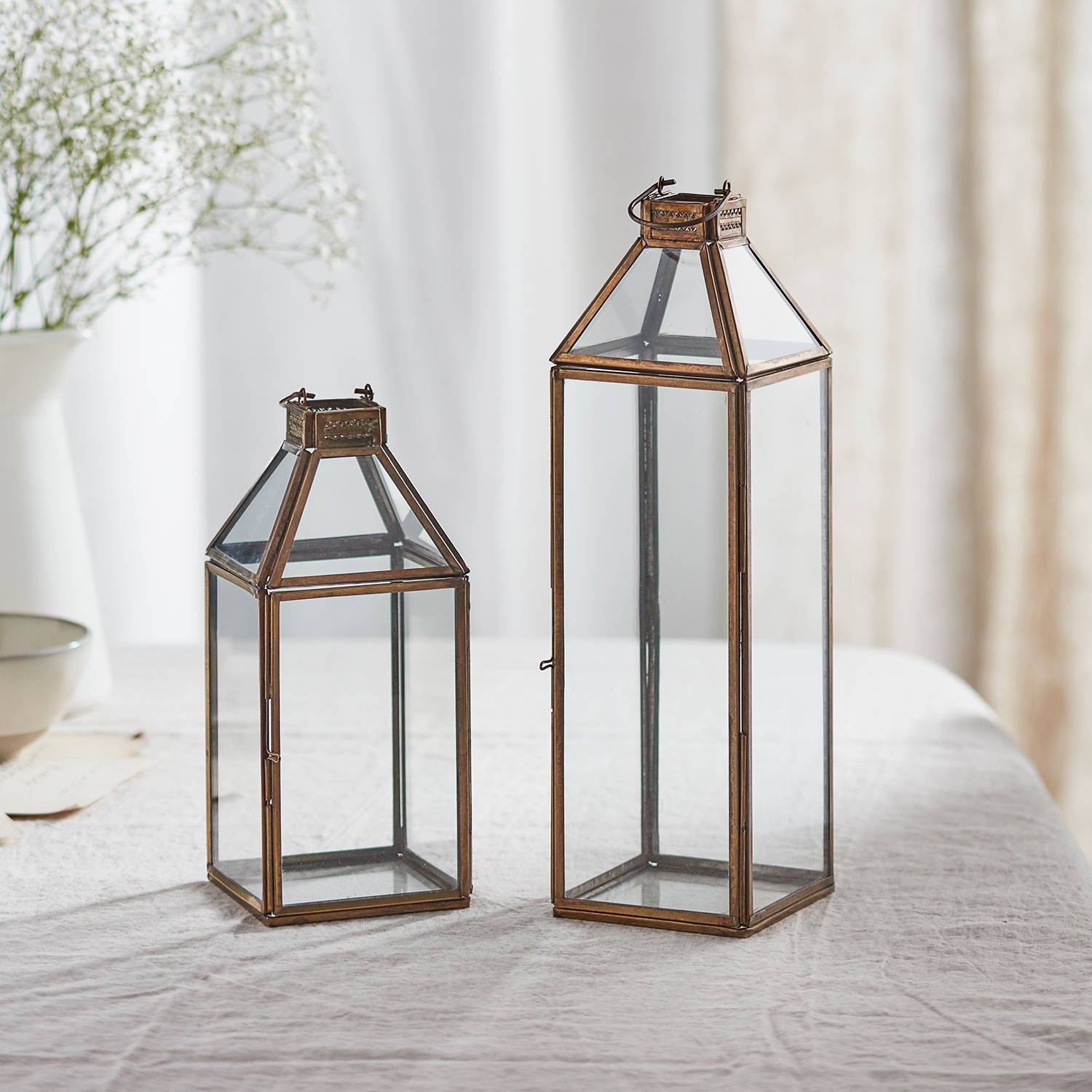 Duo of artisan glass lanterns sat on table