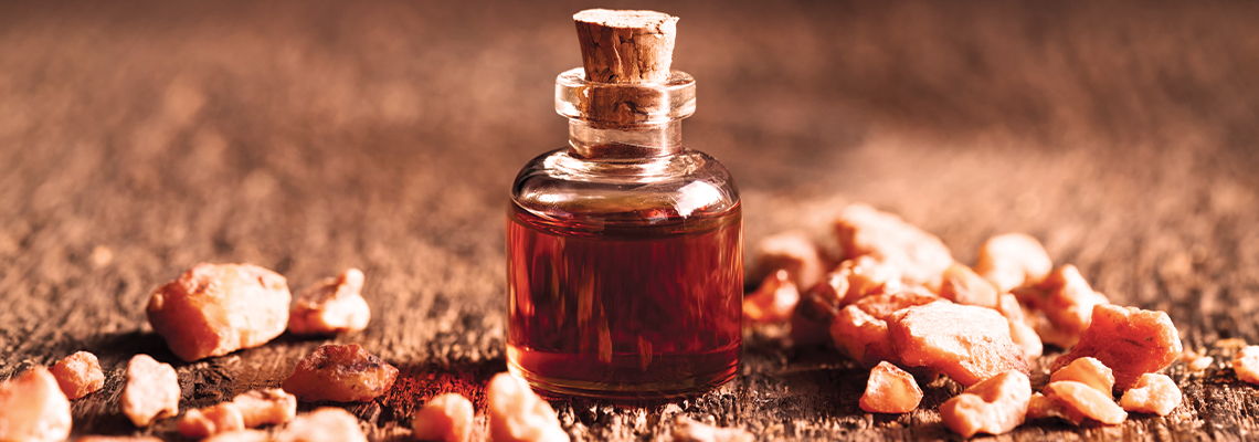 A small glass bottle of dark liquid surrounded by resin pieces.