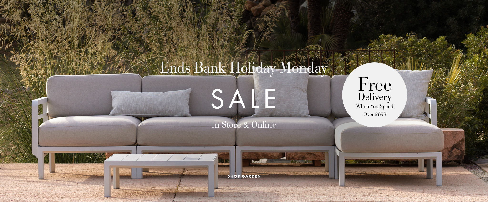 Gray outdoor sofa with cushions, promotional sale text, and free delivery offer.