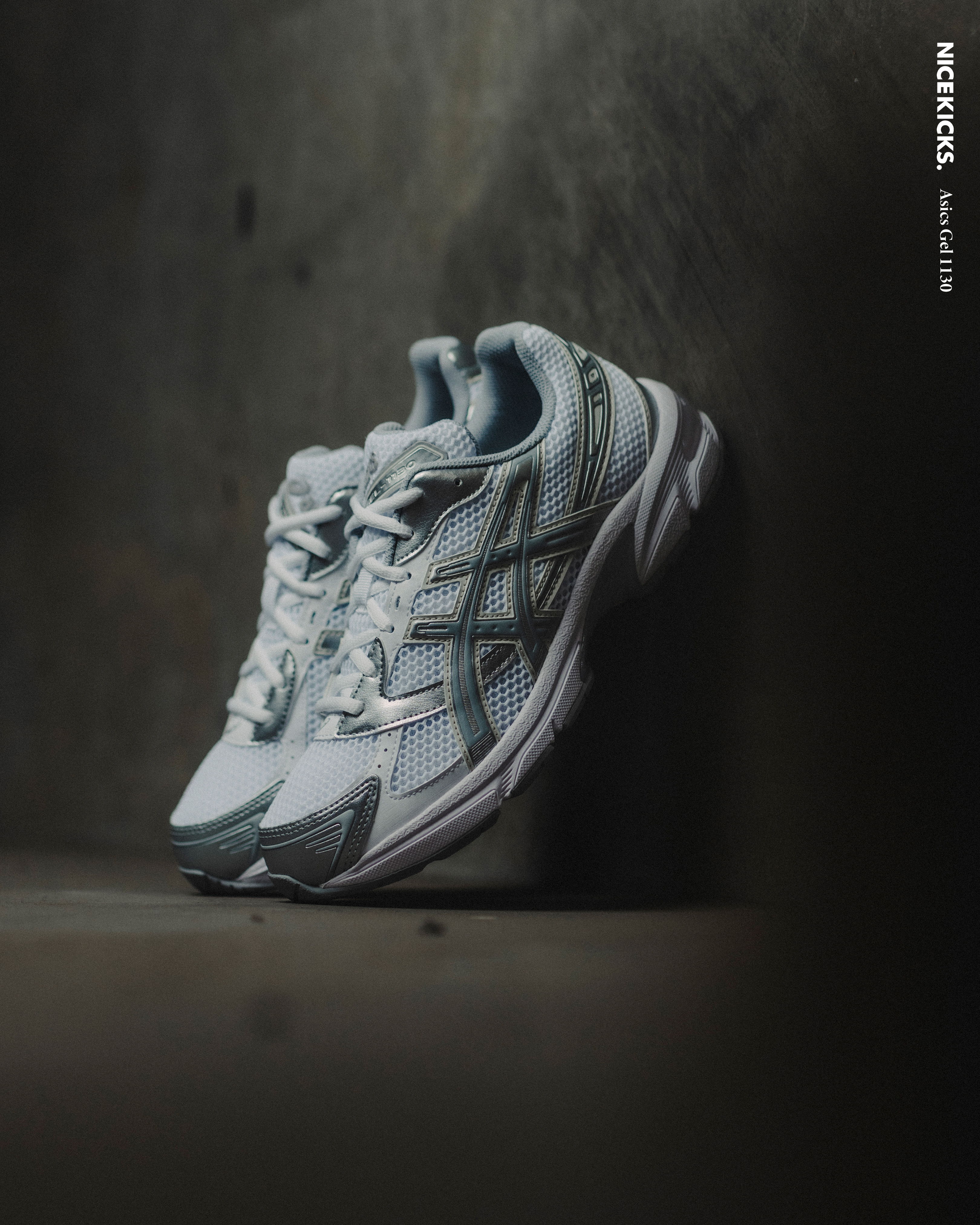 A pair of gray and white athletic shoes on a textured surface.