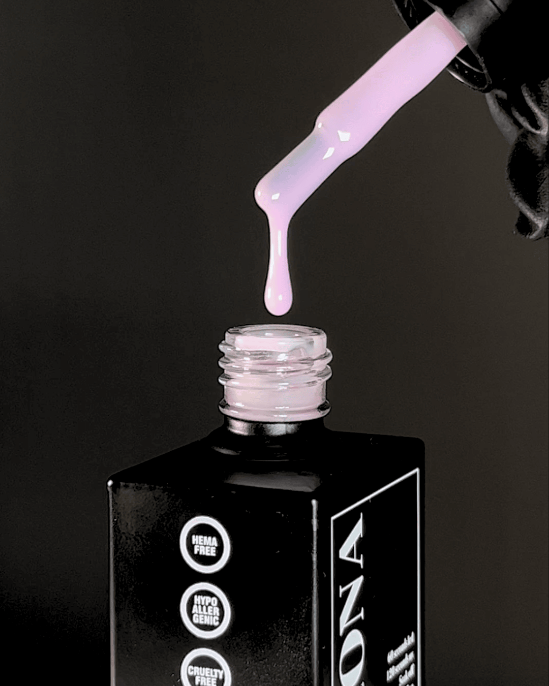 A drop of pink liquid dripping from a bottle.