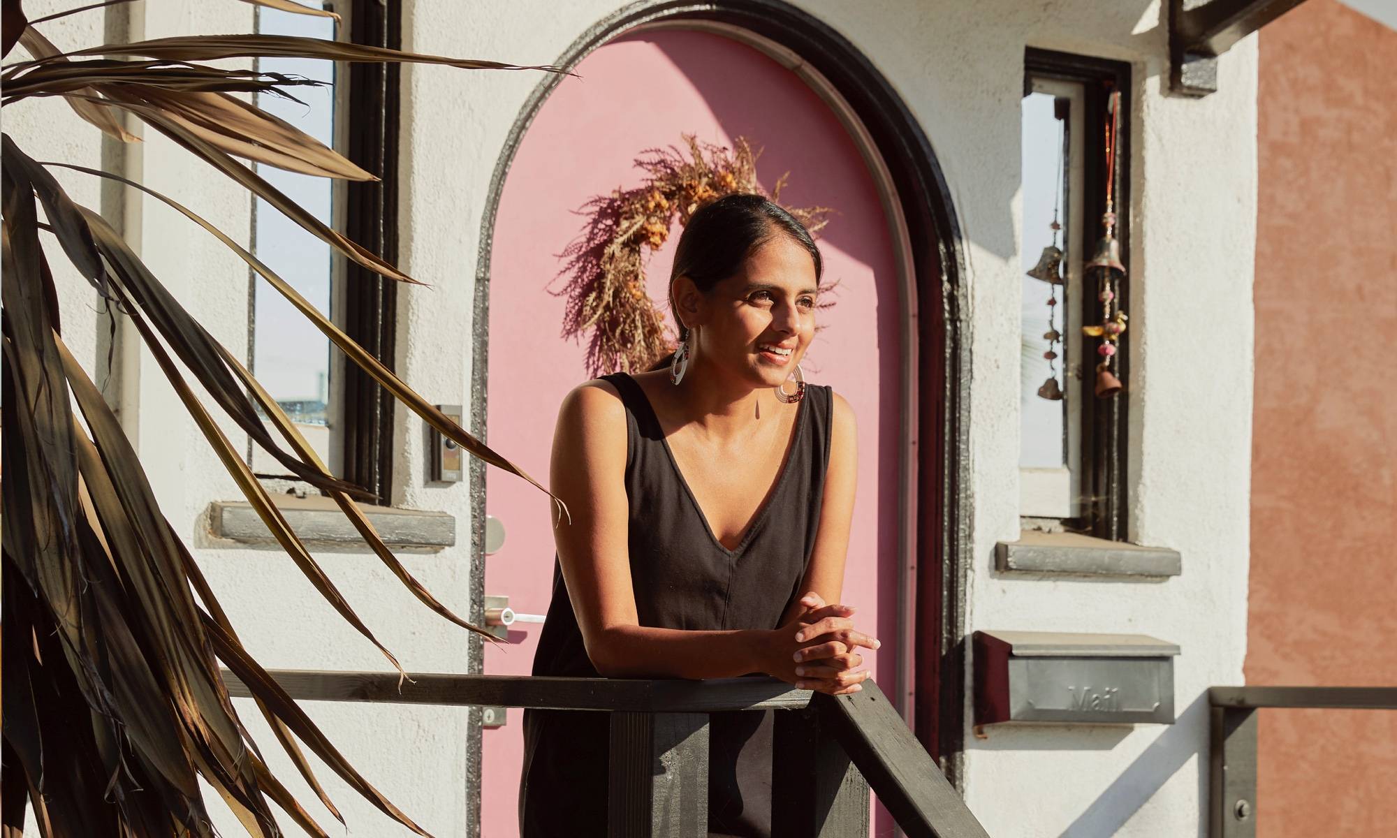 Brightland founder Aishwarya Iyer on the front porch of her LA craftsman home with pink door