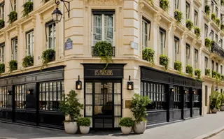 Exterior view of a stylish restaurant with plants and elegant architecture.