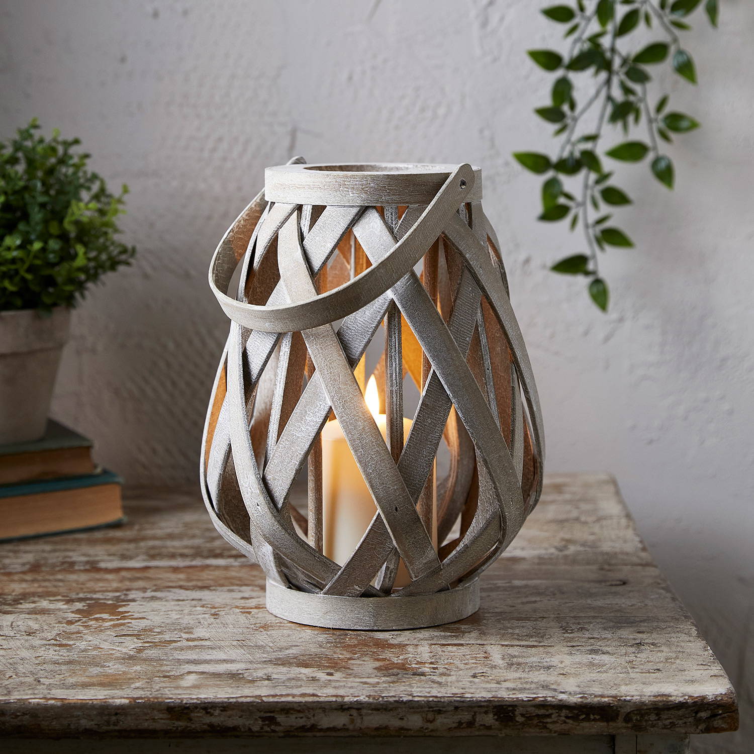 Woven lantern with TruGlow candle housed inside illuminated on table