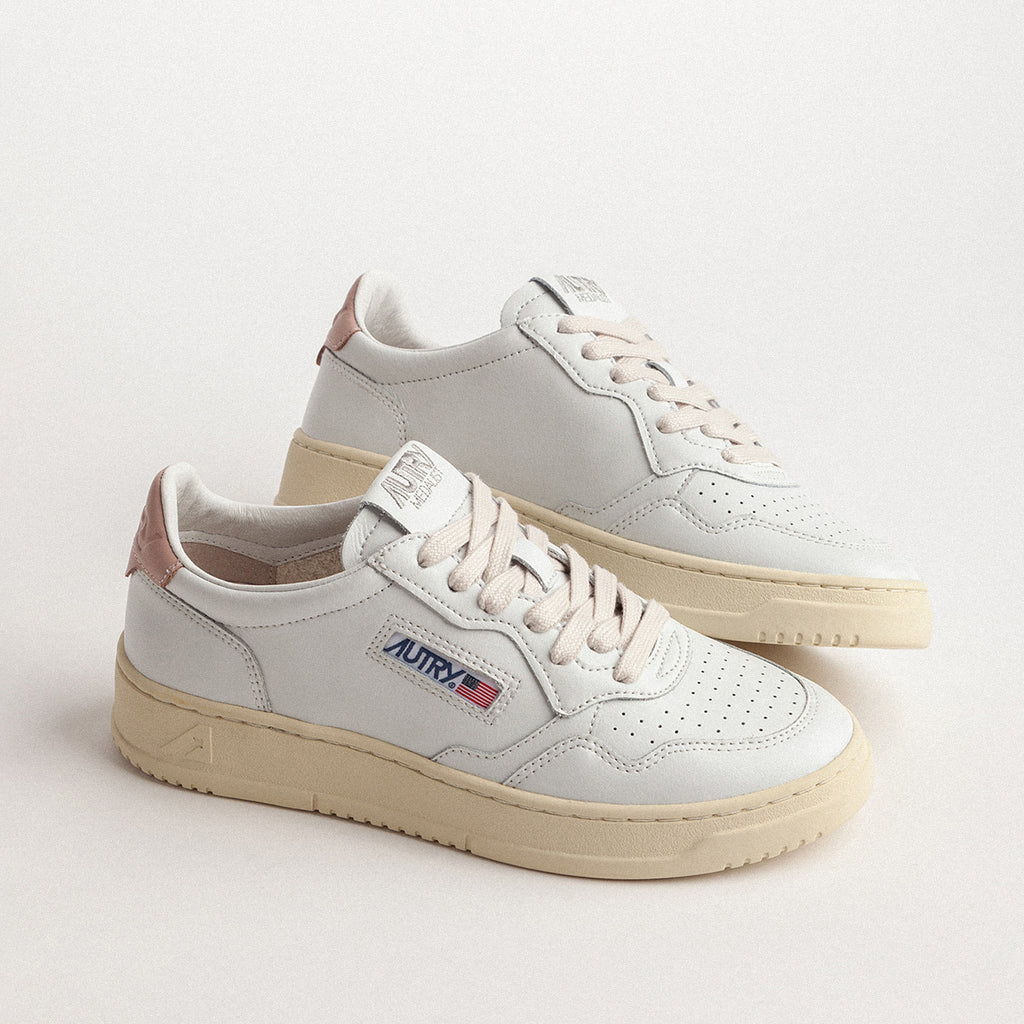 White sneakers with beige soles and a retro logo on the side.