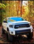 Front three-quarter white Tundra TRD Pro grille LED light bar lifted off-road tires autumn wooded trail Anthony's Outlaw 127H install gallery photo 2
