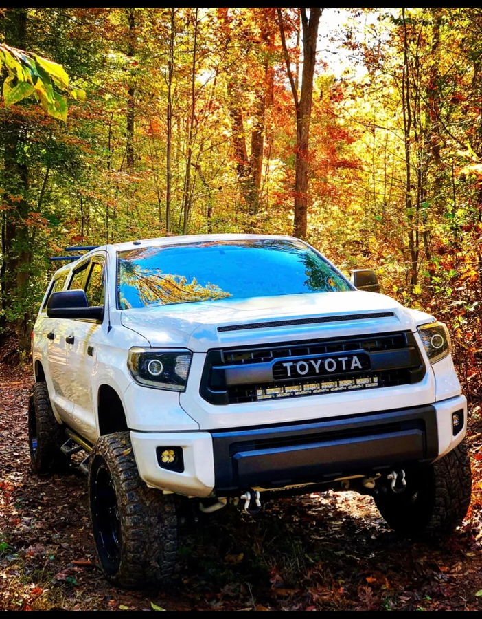 Front three-quarter white Tundra TRD Pro grille LED light bar lifted off-road tires autumn wooded trail Anthony's Outlaw 127H install gallery photo 2
