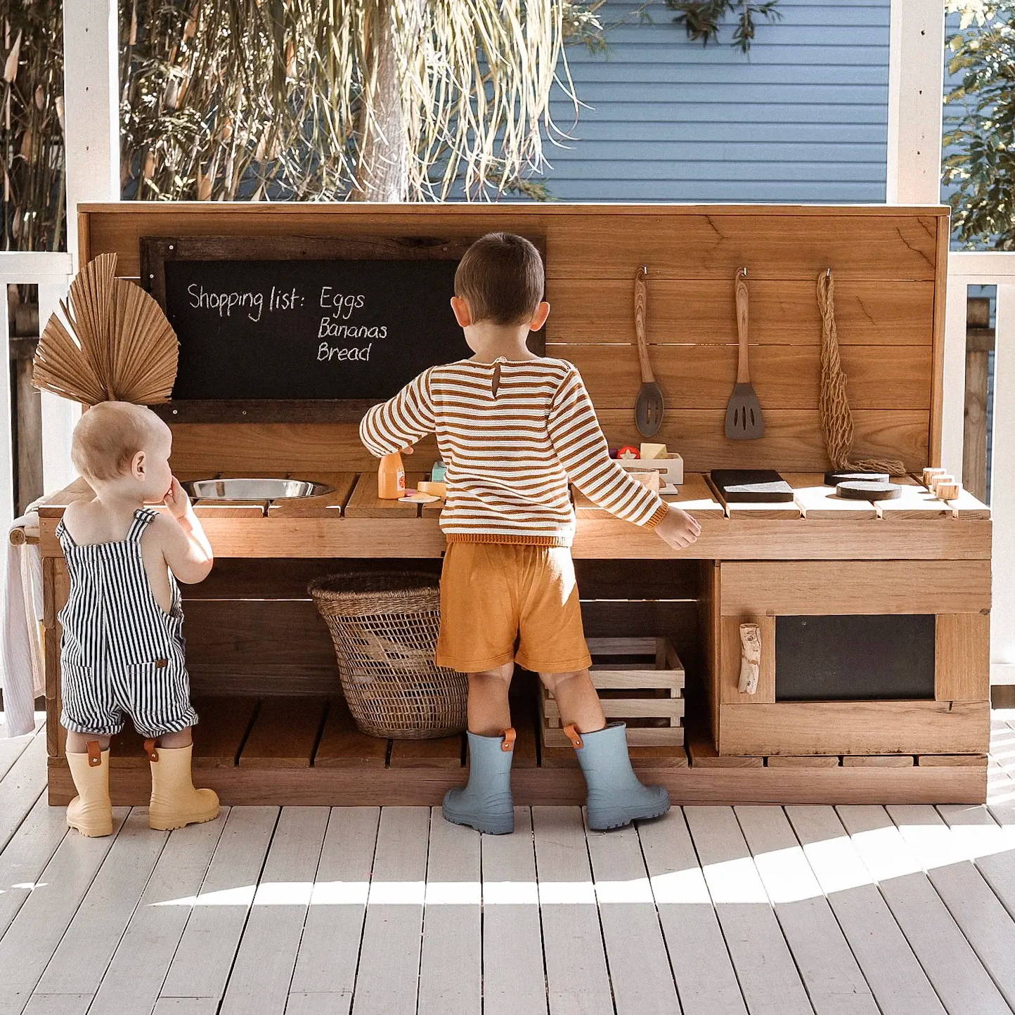 A font shot of a mud kitchen with two kids