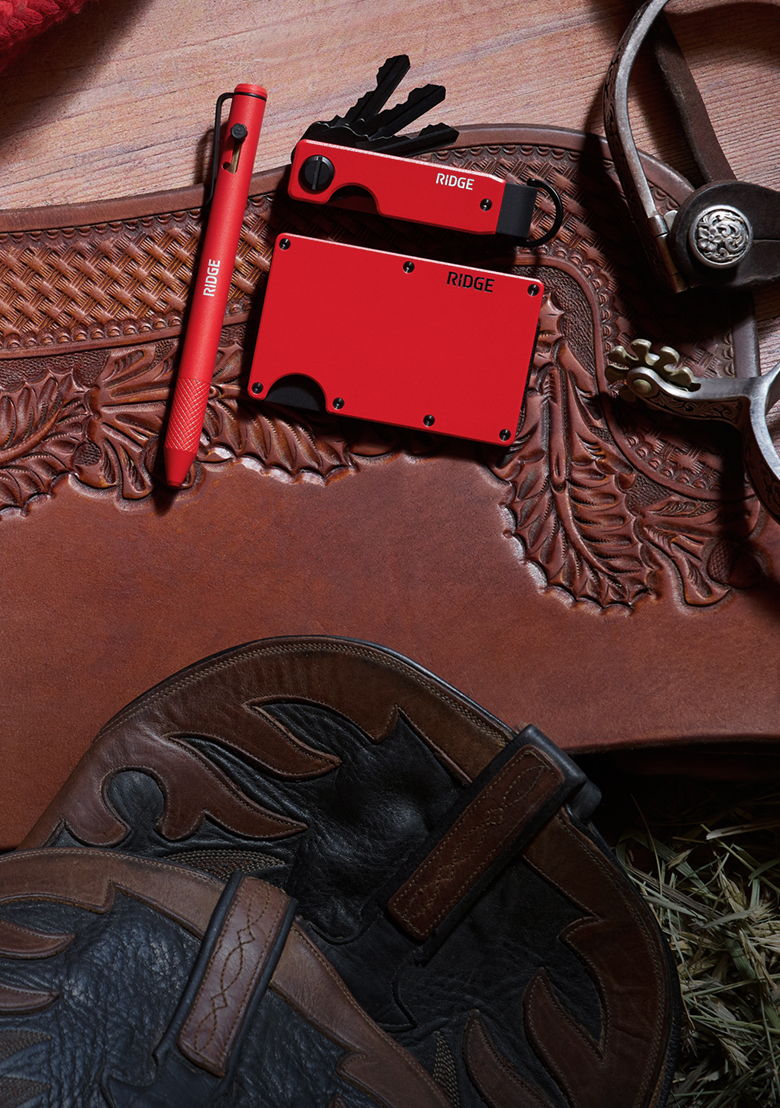 Red wallet, pen, gloves, and leather items on a textured surface.