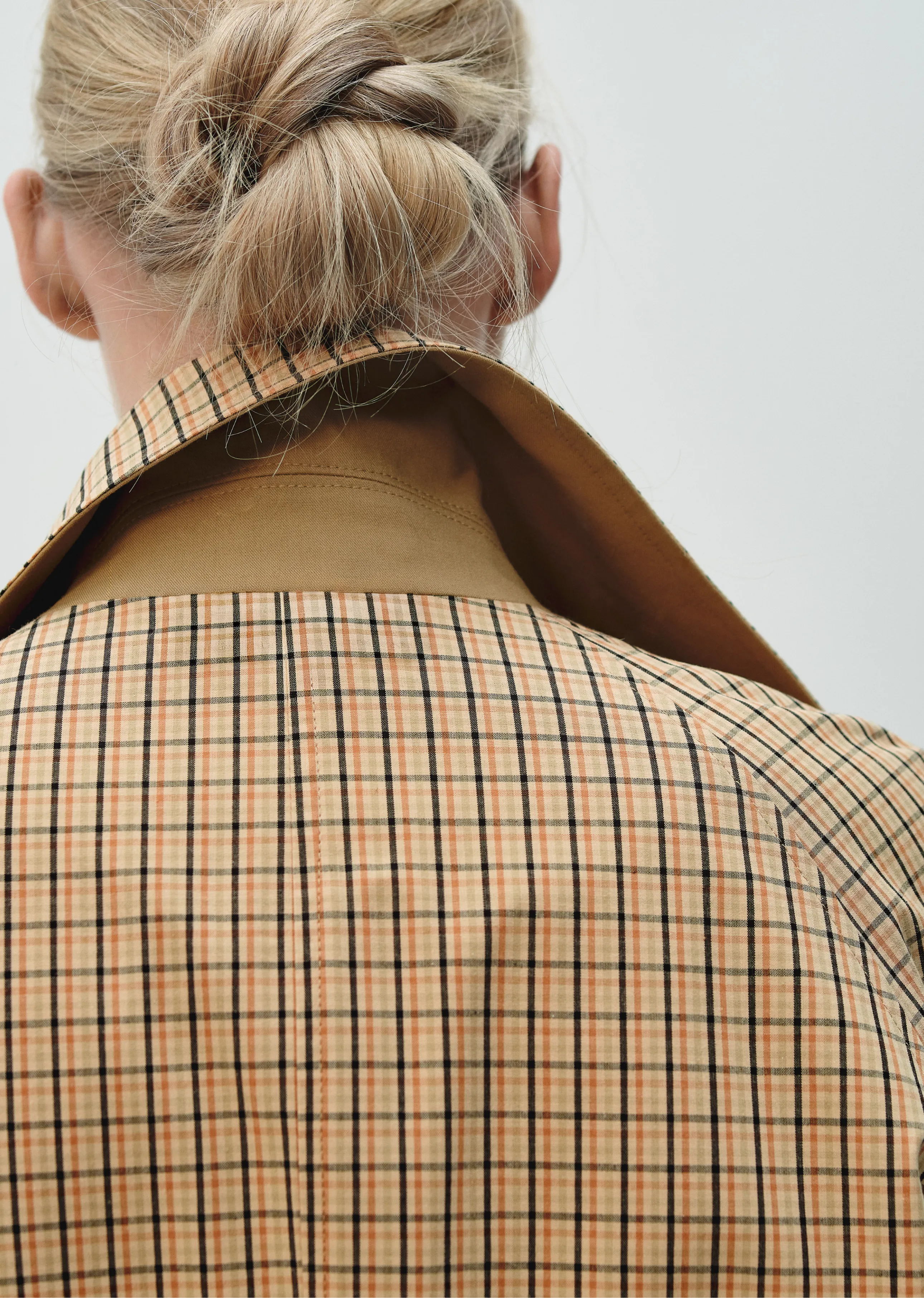 Person with a bun wearing a checkered coat, viewed from behind.