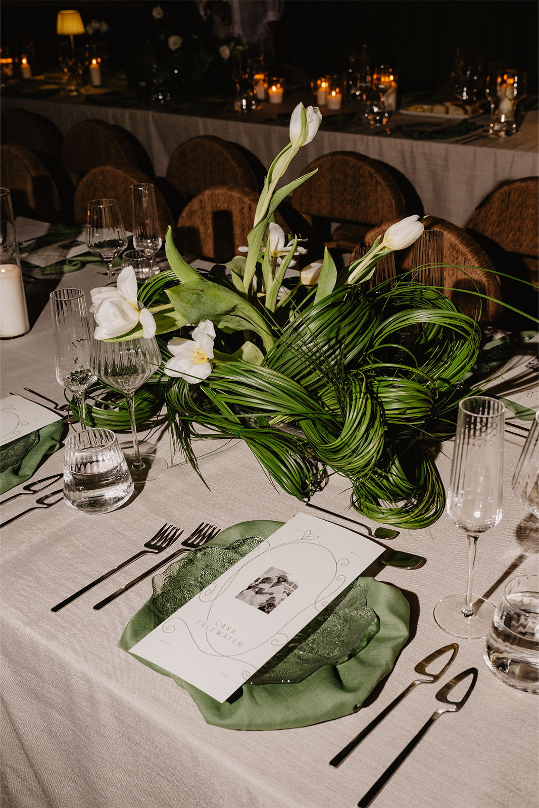 Table setting with floral arrangement and menu on a green napkin.