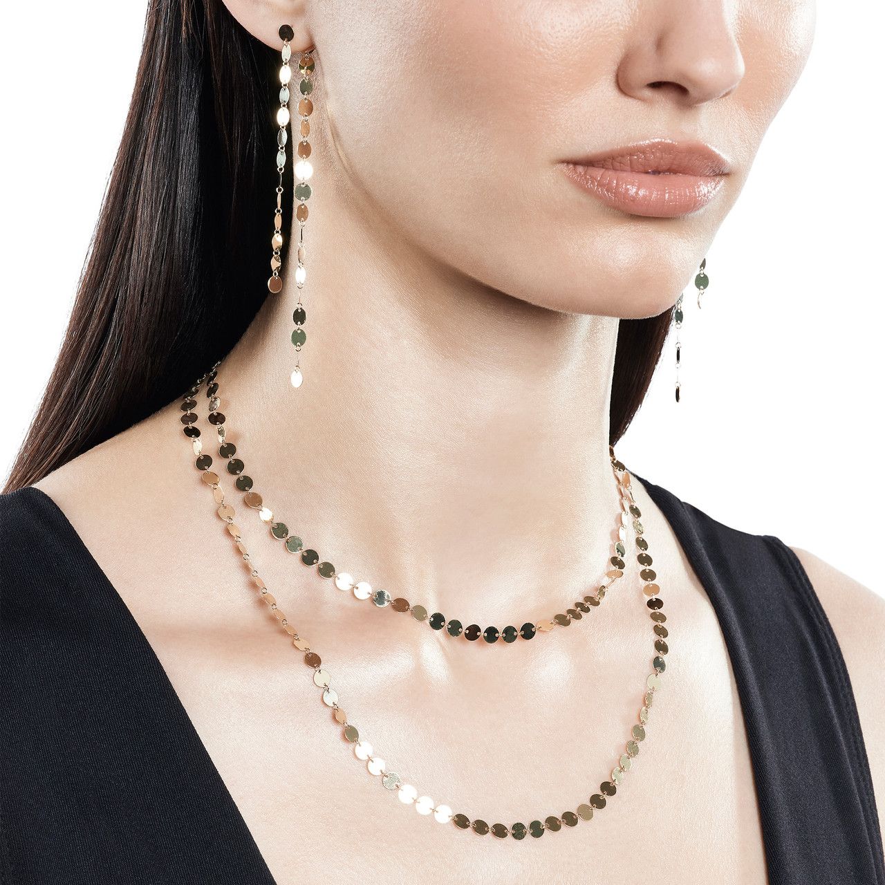 Close-up of a model wearing layered necklaces and long earrings.