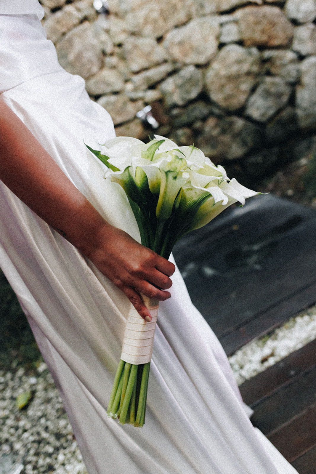 A bride holding a bouquet of calla lilies in a white dress.