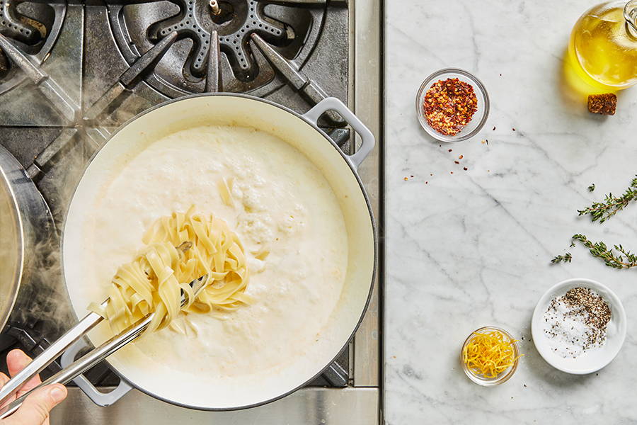 Cooked pasta added to creamy sauce.