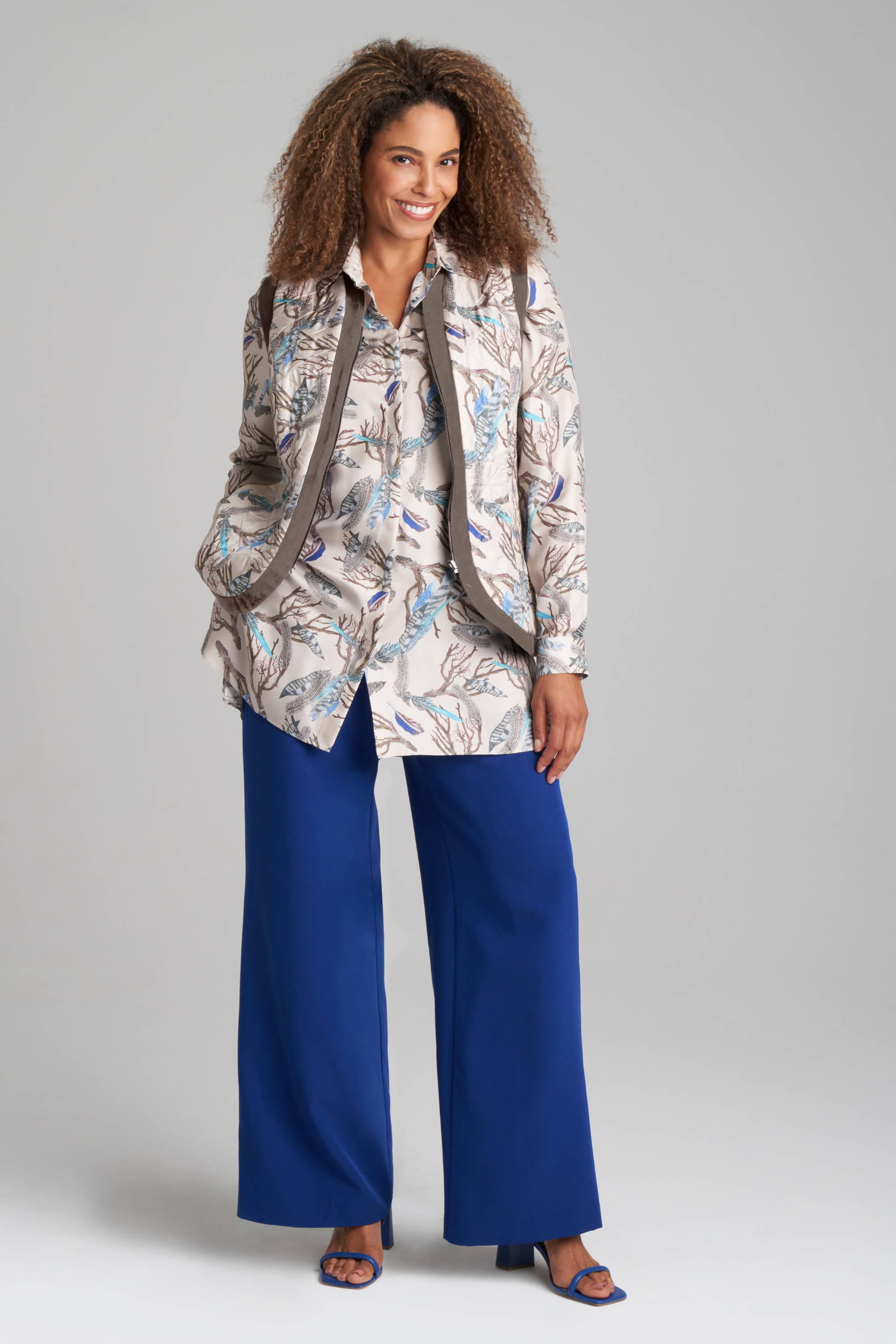Woman wearing feather printed reversible silk vest over silk shirt with blue pants by Ala von Auersperg