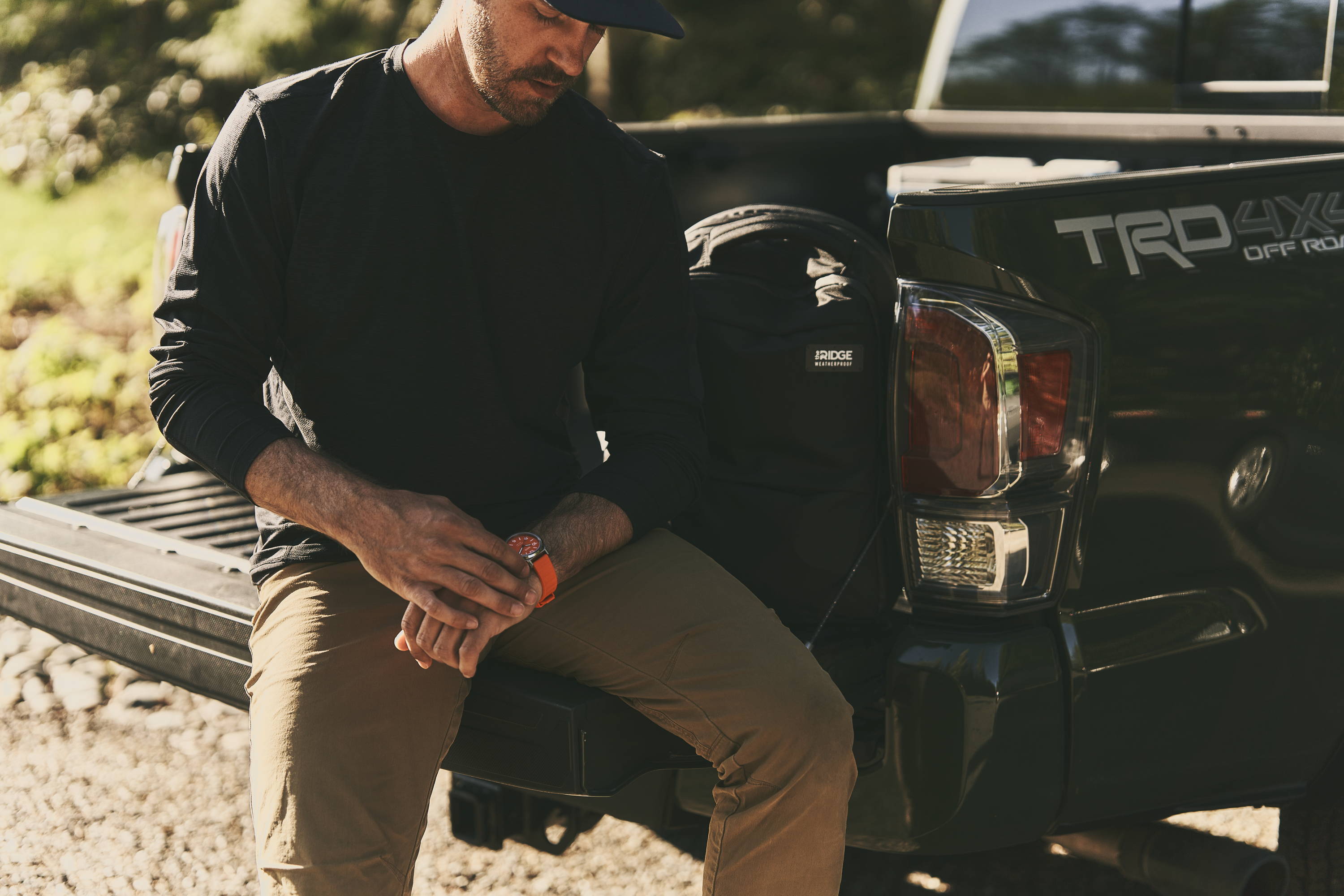 man sitting on a truck bed looking down at the ridge titanium field watch