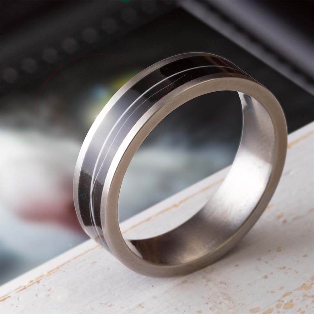 A sleek metallic ring with two black stripes on a surface.