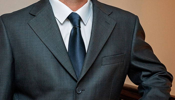 Man wearing a navy blue tie and gray suit