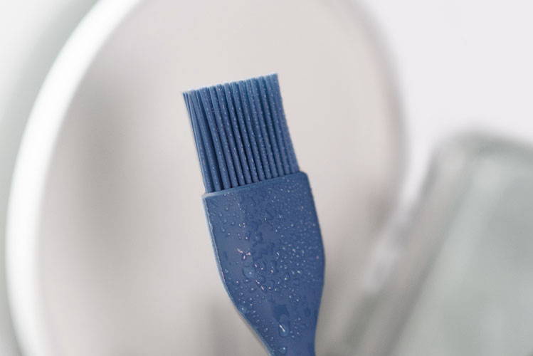 A Blue Misen Pastry Brush just washed in a dishwasher, covered in small water droplets.