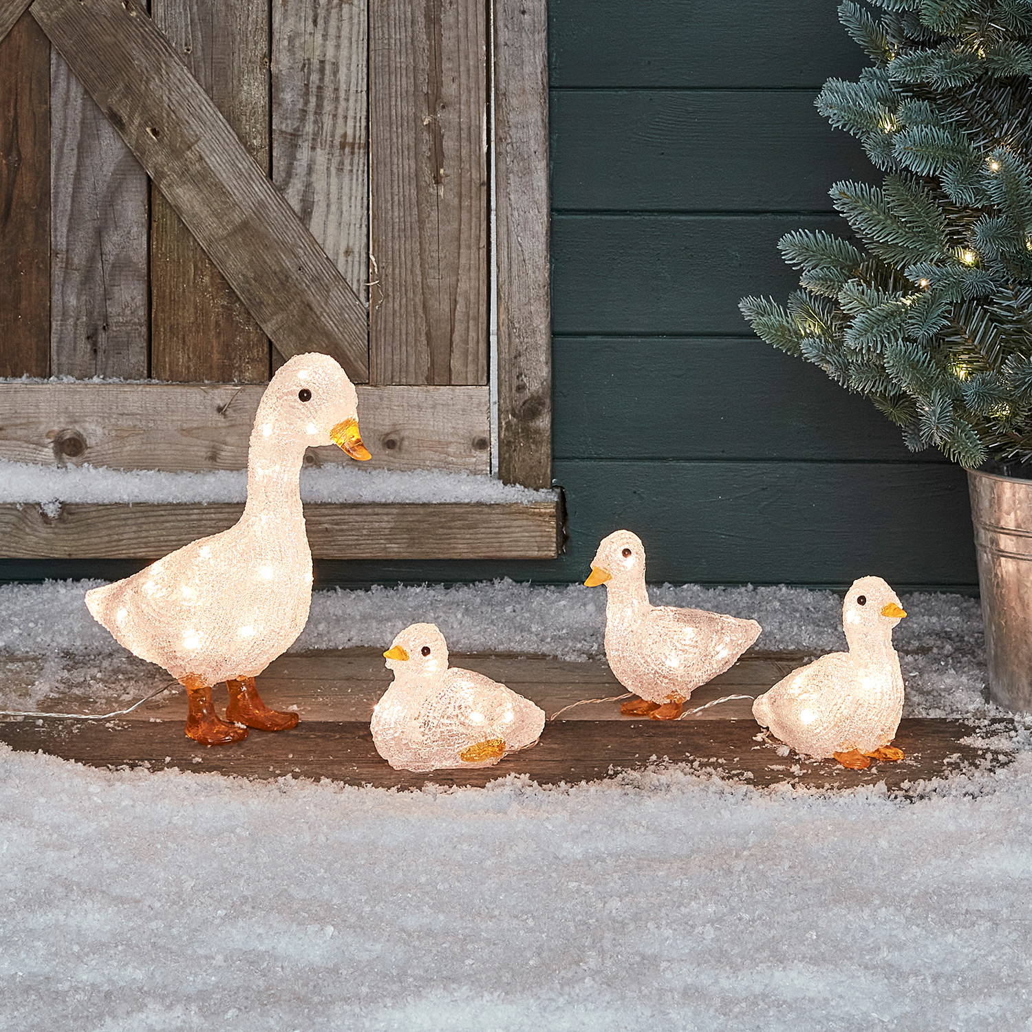 Acrylic duck family sitting in a frosted garden setting with mini Christmas tree