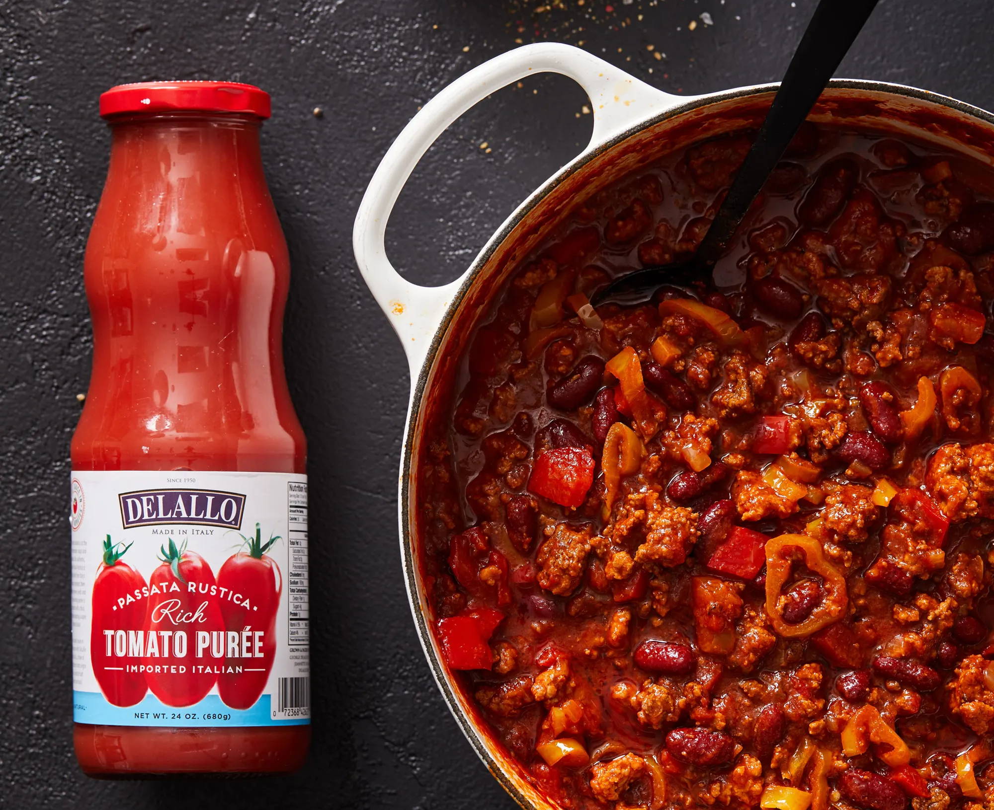 A jar of DeLallo tomato Passata next to a pot of chili