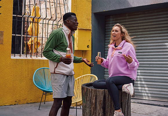 Man & woman in stylish Columbia fleece having a health drink.