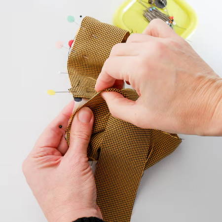 Hands pinning a fabric strip to a curved piece of fabric