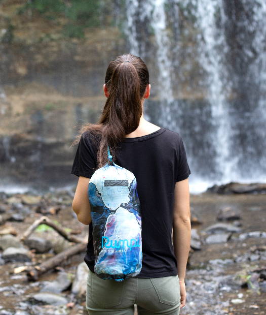 Kelly Marie holding her Rumpl blanket stuff sack by a waterfall