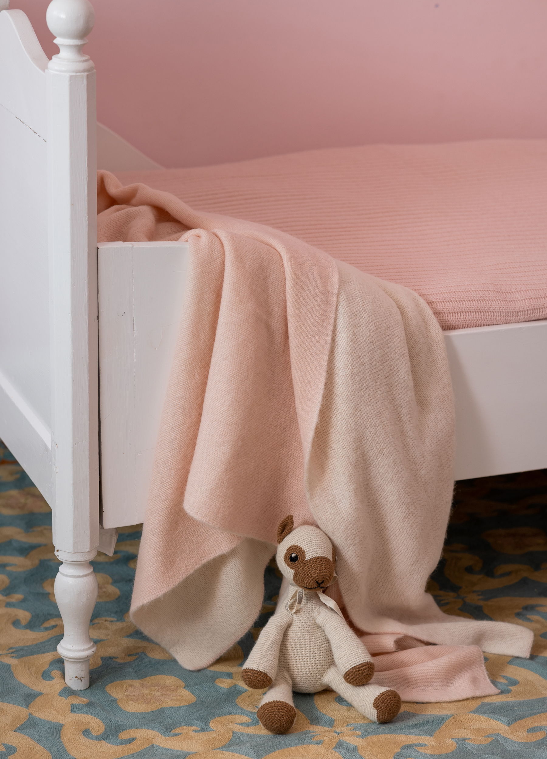 A cozy bedroom corner with a pink blanket and a stuffed animal.
