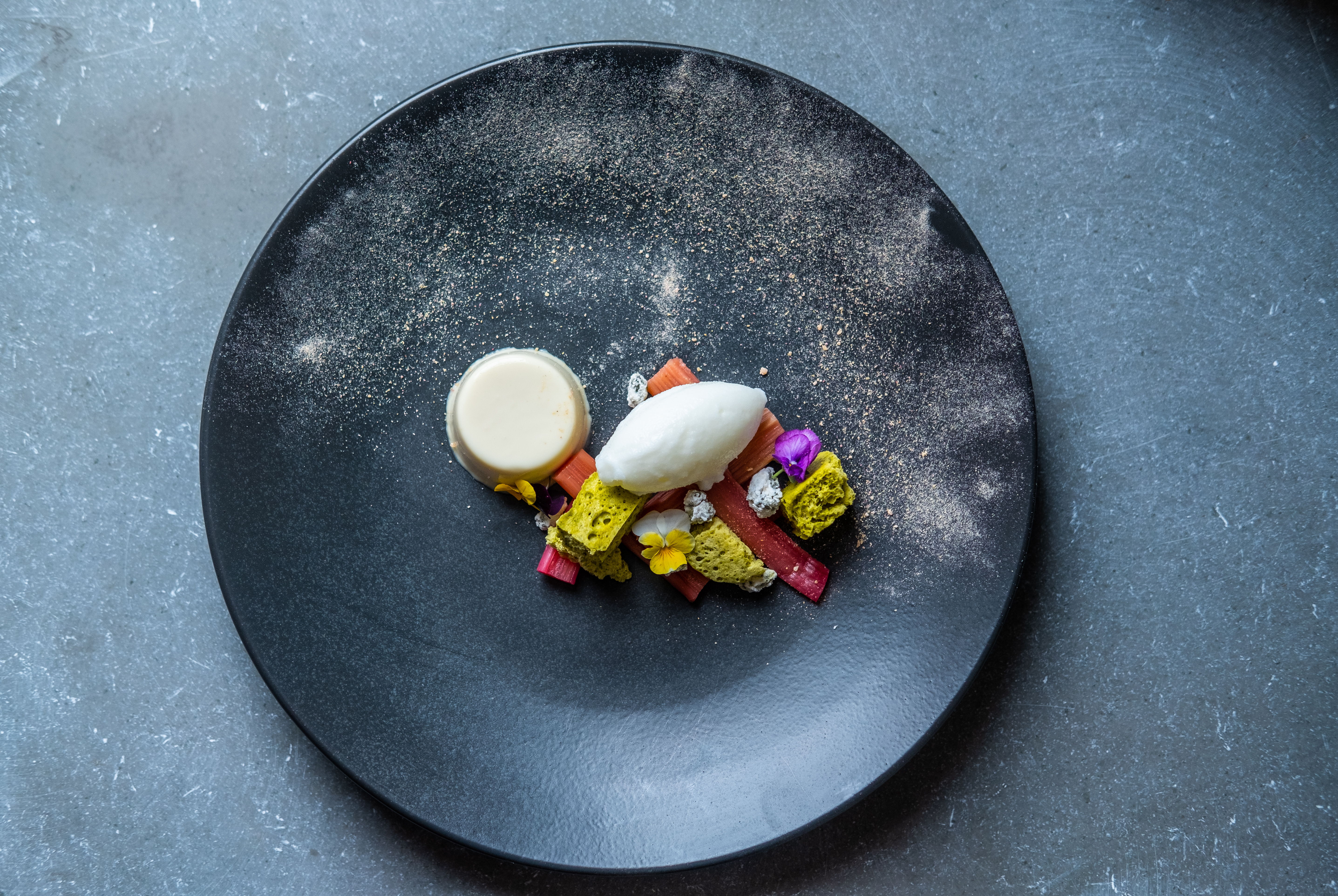 Dessert plate with ice cream and colorful candies on a dark background.