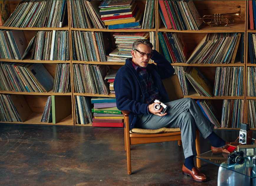 Person sitting in a chair with vinyl records in the background.