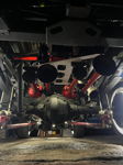 Four red train horns mounted to white plate above differential in indoor garage