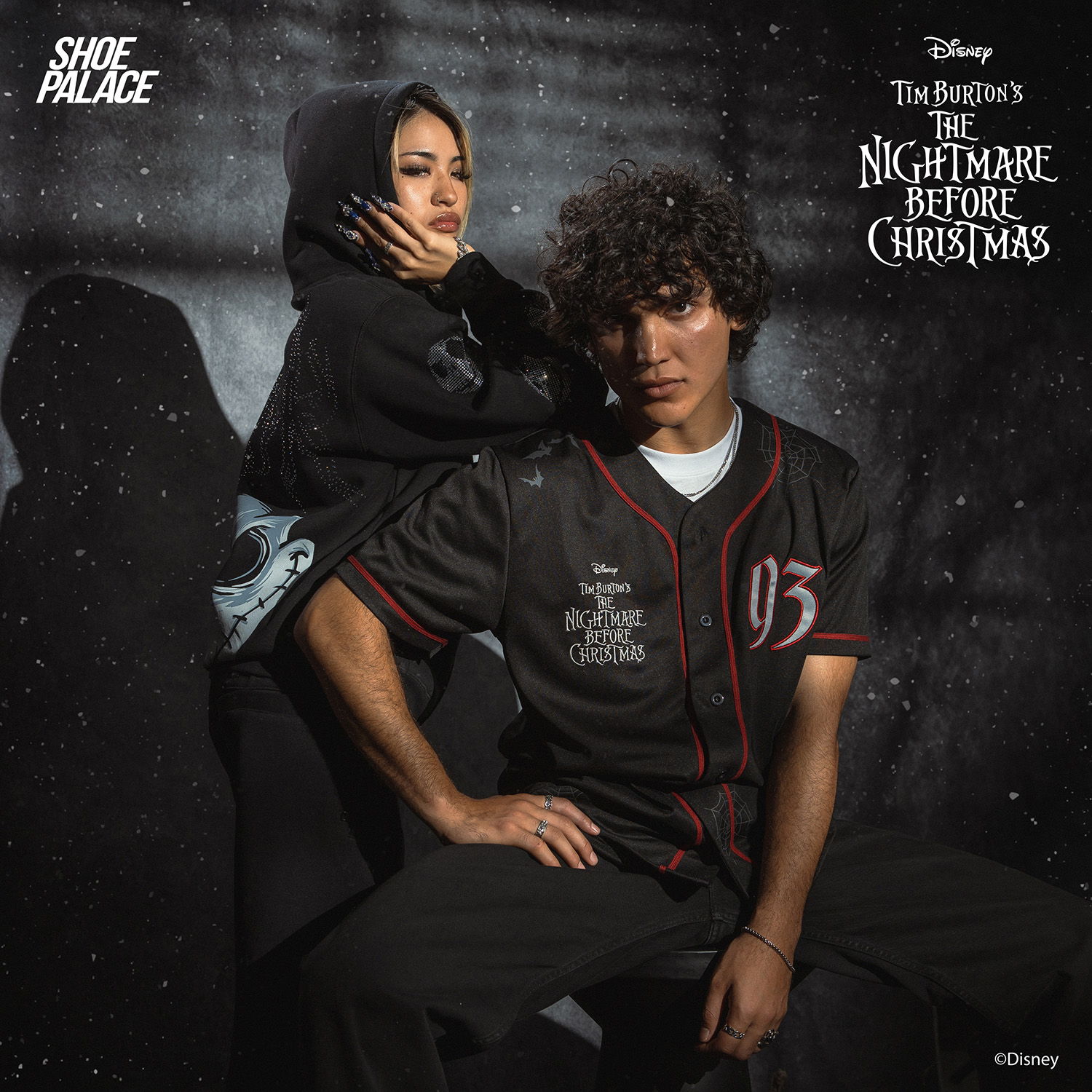 Two individuals posing in stylish outfits with a dark background.