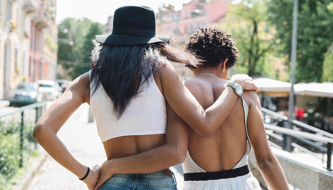 Two women walking with arms around each other. heroimage