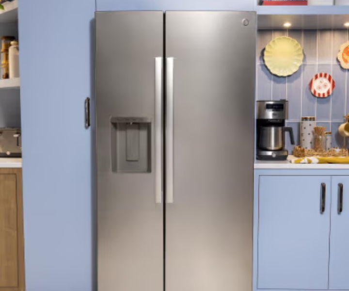Stainless steel refrigerator in a modern kitchen setting with blue cabinets.