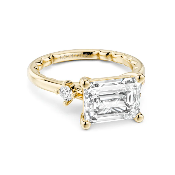 A gold ring featuring a large emerald-cut diamond and smaller accent diamonds.