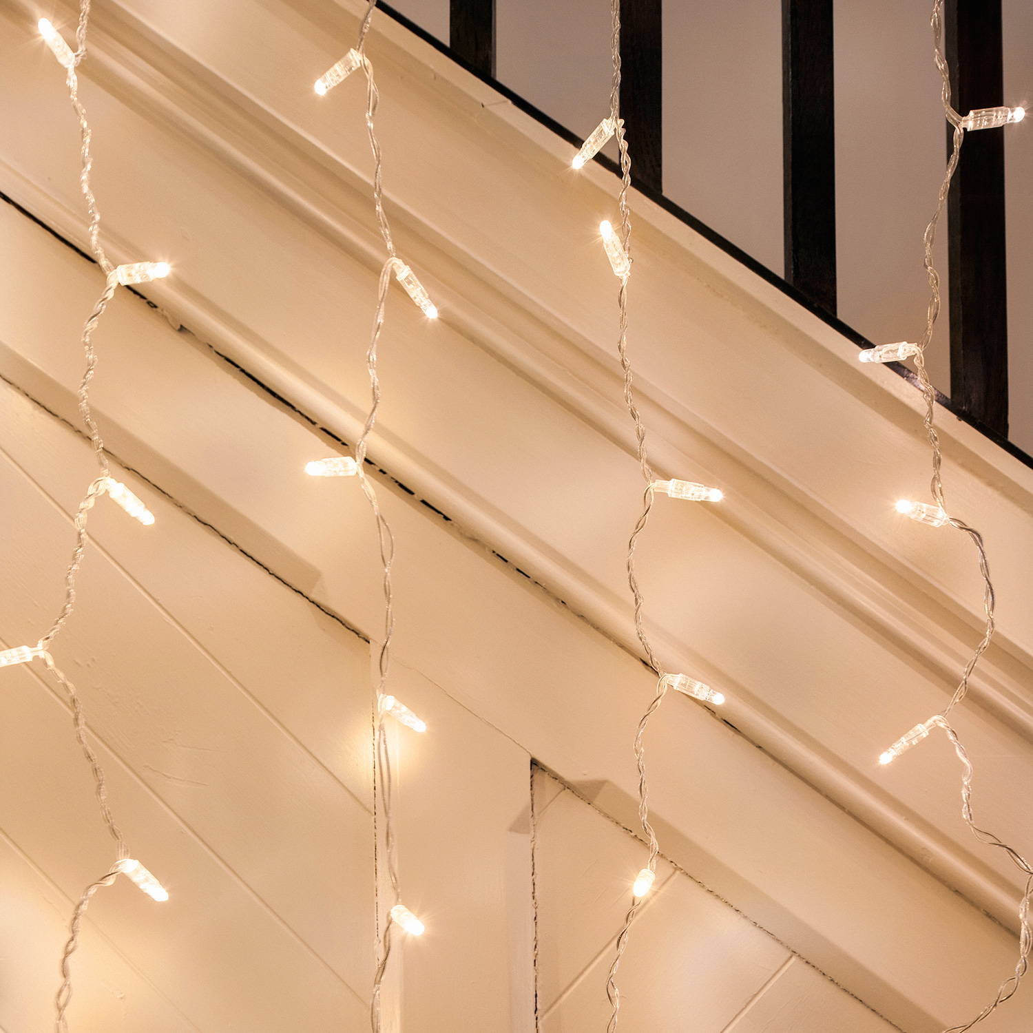 A close up of warm white led curtain lights hanging over a banister