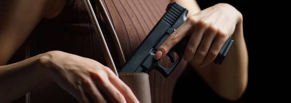 Female putting concealed carry handgun into purse