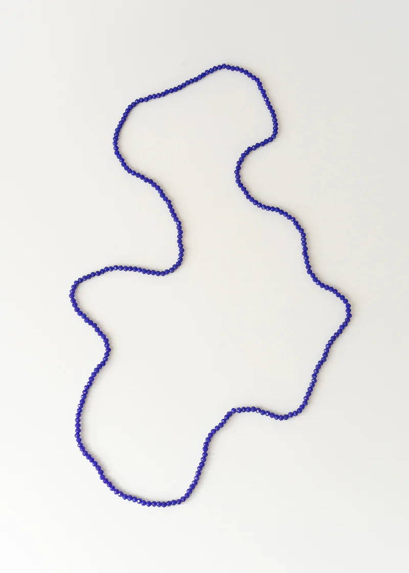 A dark blue small beaded necklace on a white background