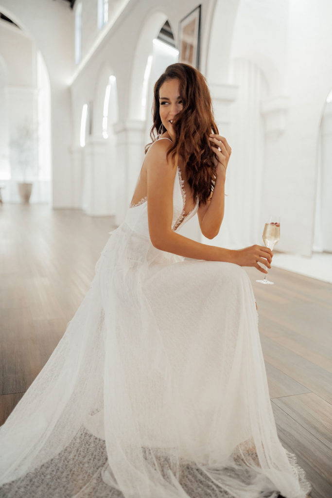 Bride holding champagne wearing the Grace Loves Lace Song wedding dress